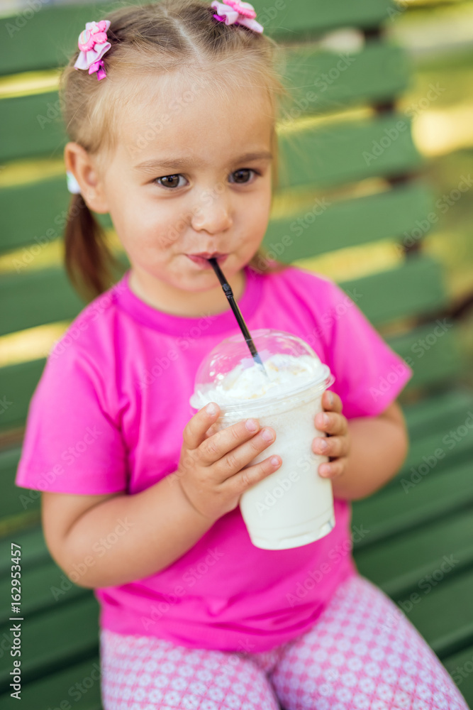 Fototapeta premium Little girl drinking milkshake through a straw
