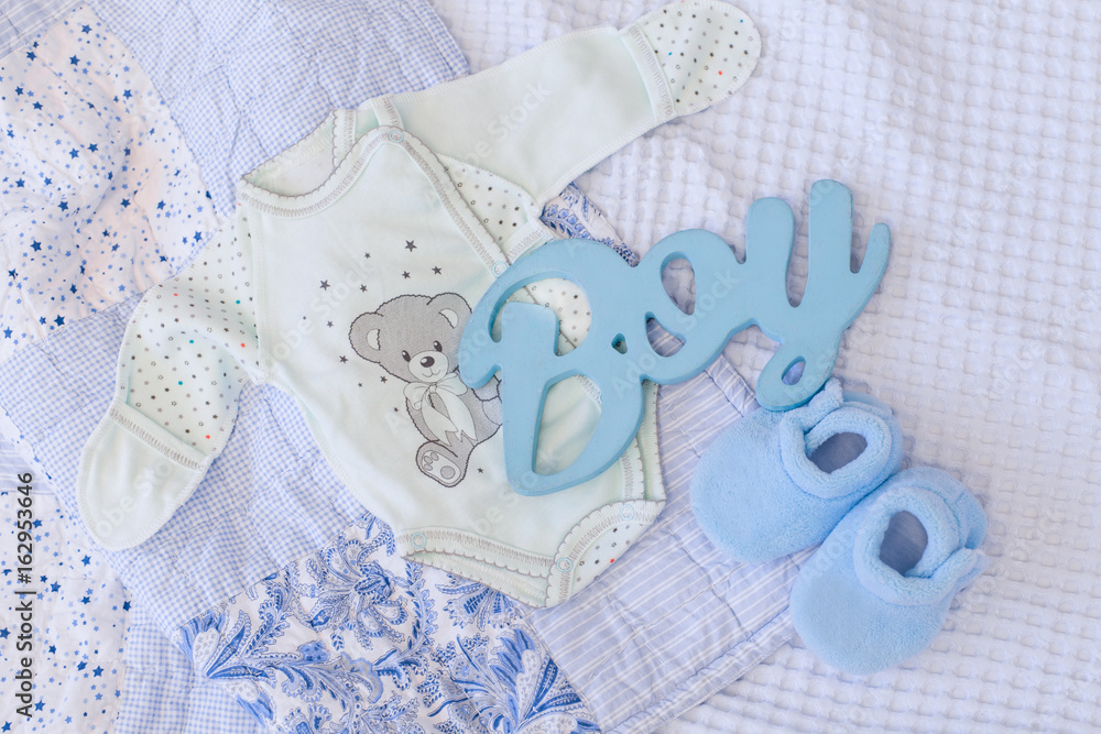 Anticipation of baby boy. Composition with clothes, boots and wood letters in blue color. Baby boy shower. Anticipation of baby boy. Composition with clothes, boots and wood letters in blue color. Baby boy shower.