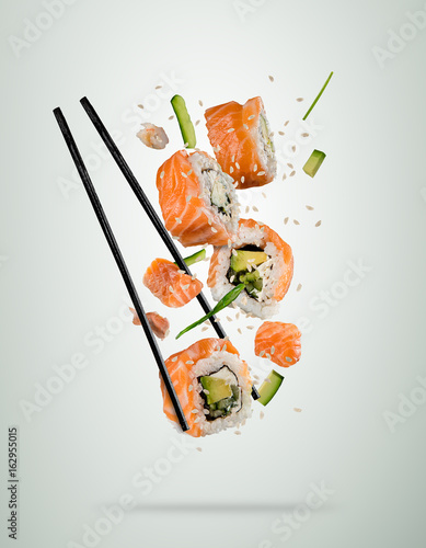 Flying sushi pieces with chopsticks, separated on soft background