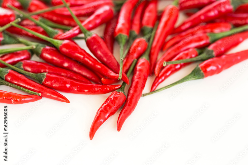 red hot chili peppers, popular spices concept - beautiful handful of red hot pepper in bulk, fresh ripe pods with green peduncle scattered on white background, flat lay, free space for the text.