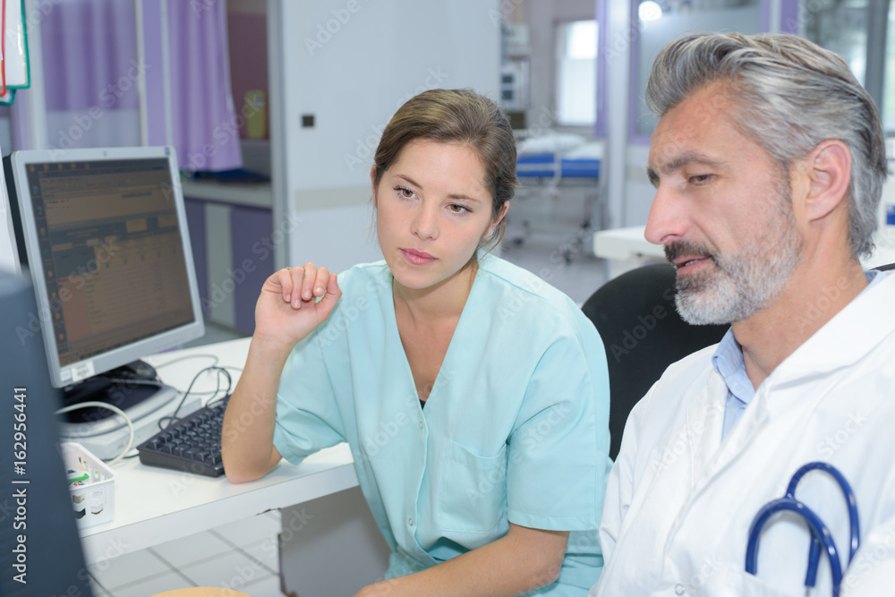 female doctor with male nurse working at nurses station female doctor with male nurse working at nurses station