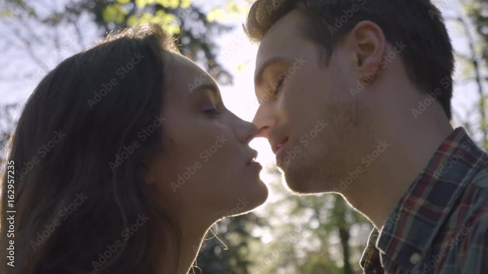 Closeup Of Cute Couple, Backlit By Sun, They Kiss, Then Man Kisses Girlfriend On Cheek Closeup Of Cute Couple, Backlit By Sun, They Kiss, Then Man Kisses Girlfriend On Cheek