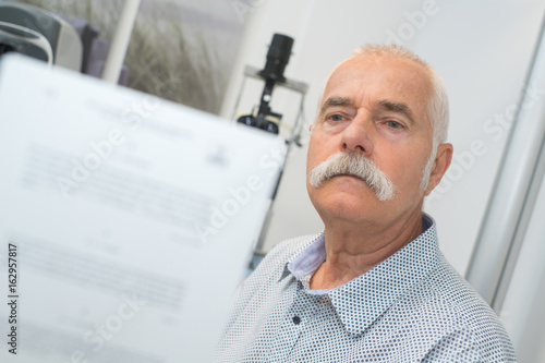 doctor asking patient to read chart behind him