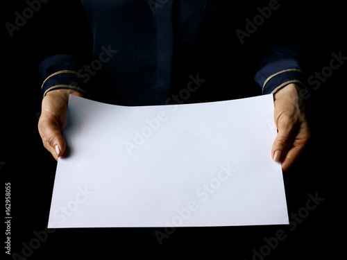 female hands isolated on black showing blank paper sheet photo