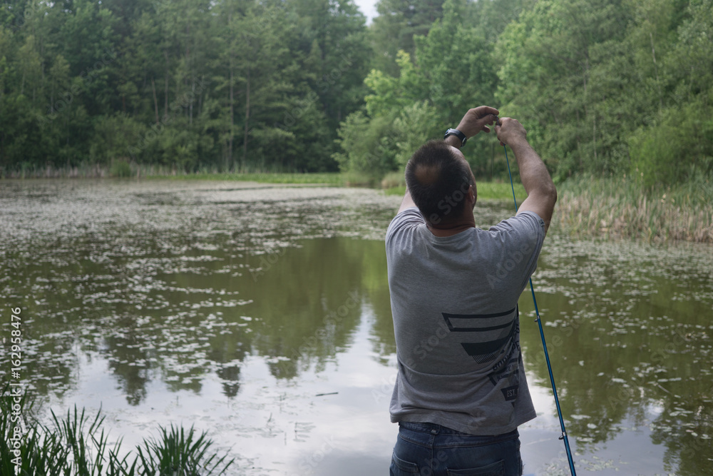 a man starts fishing on the pond in a forest in summer