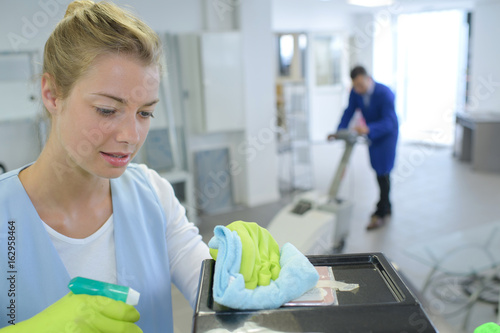 female cleaner cleaning corridor of business building