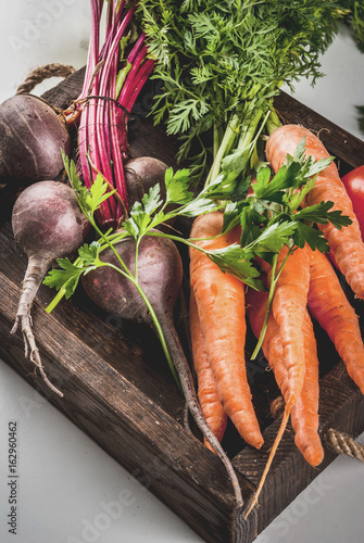Summer, autumn harvest. Fresh organic farm vegetables in a wooden box on a white marble table - beets, carrots, parsley, tomatoes. Copy space top view