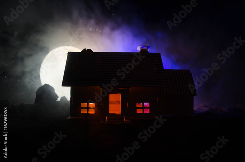 Old house with a Ghost in the moonlit night or Abandoned Haunted Horror House in fog, Old mystic villa with surreal big full moon. Horror concept