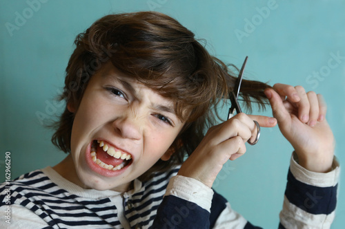 teenager boy cut his hair with scissors close up photo photo