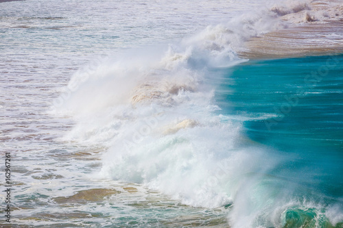blue wave crashes down at the beach in El Cotillo village in Fuerteventura island, Spain