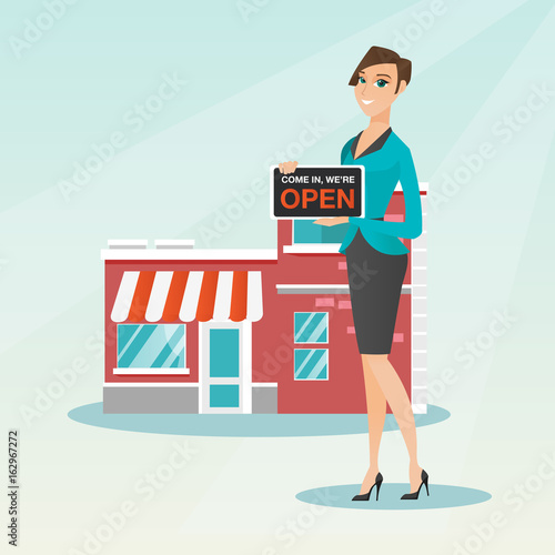 Caucasian shop owner holding open signboard.