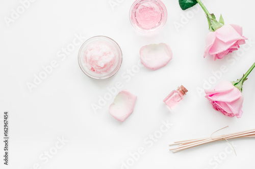 cosmetic set with rose blossom and body cream on white desk background top view mock-up