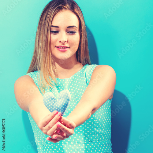 Happy young woman holding a heart cushion