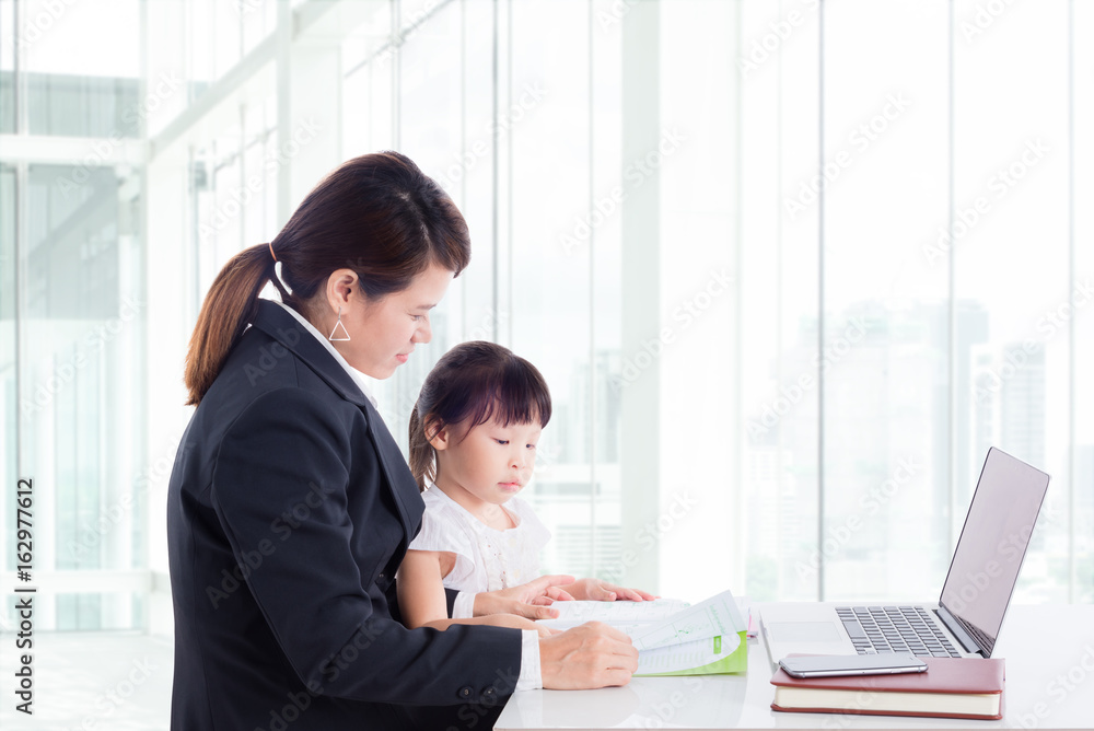 Asian businesswoman reading book with daughter at office Asian businesswoman reading book with daughter at office