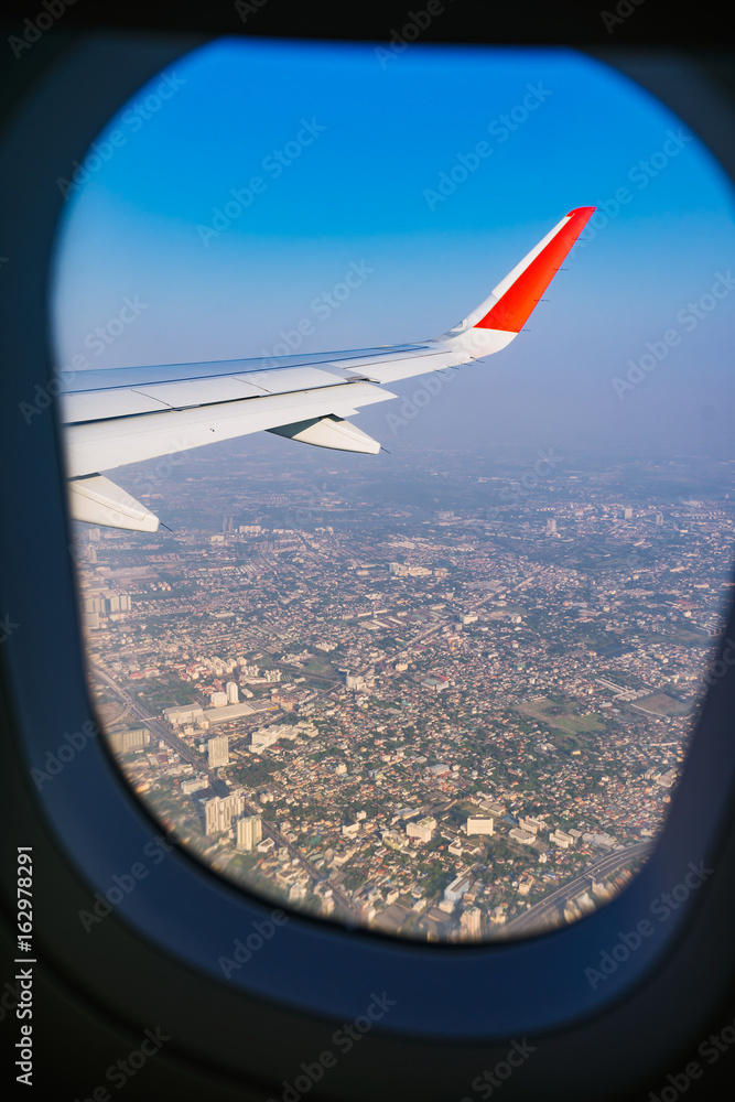 View of plane wing with cityscape from the airplane window.