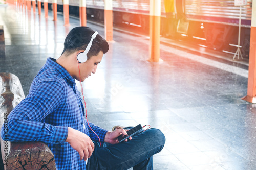 Traveler Man using tablet and headphone waiting for train on the station © joyfotoliakid