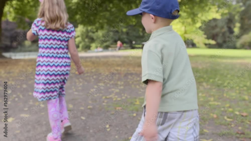 Silly Little Kids (Brother And Sister) Walk Funny On A Park Path In Autumn (Slow Motion) Silly Little Kids (Brother And Sister) Walk Funny On A Park Path In Autumn (Slow Motion)