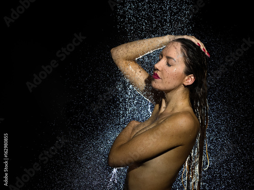 Attractive naked young woman taking a shower