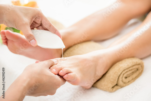 Therapist pouring oil to a woman foot