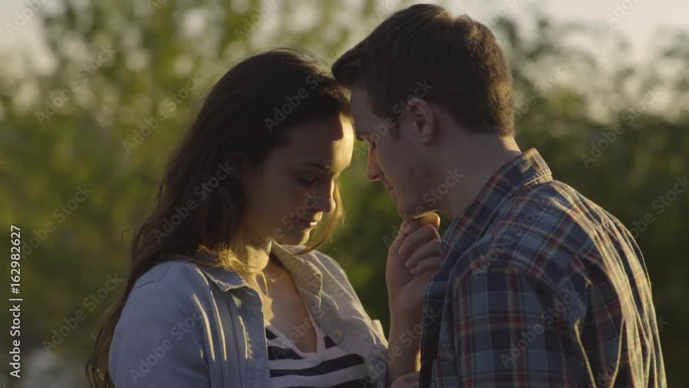 Closeup Portrait Of Couple Having Intimate Moment At Sunset, They Turn And Look At Camera Closeup Portrait Of Couple Having Intimate Moment At Sunset, They Turn And Look At Camera