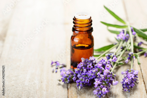 Lavender essential oil in the amber bottle  with fresh lavender flower heads.