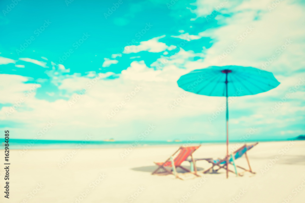 Blurred white sand beach with beach chairs and parasol
