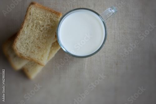 A glass of milk and pieces of white bread.