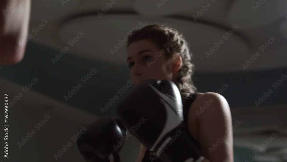 Young attractive woman in boxing gloves training with her coach in a boxing club. Slow motion shot Young attractive woman in boxing gloves training with her coach in a boxing club. Slow motion shot