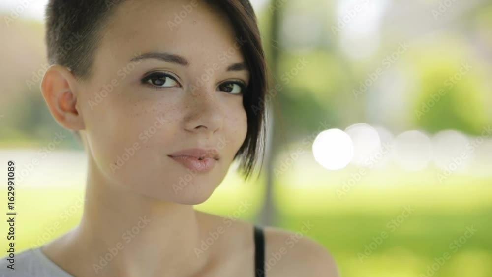 Pretty cute woman closeup portrait looking to camera at summer day. Beautiful female face in slow motion. Pretty cute woman closeup portrait looking to camera at summer day. Beautiful female face in slow motion.