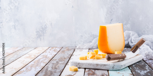 Foto Delicious dutch gouda cheese with cheese cubes and special knife on old wooden table