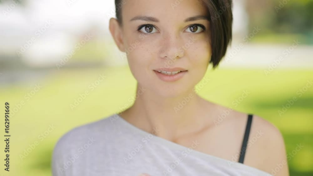 Pretty cute woman closeup portrait looking to camera at summer day. Beautiful female face in slow motion. Pretty cute woman closeup portrait looking to camera at summer day. Beautiful female face in slow motion.