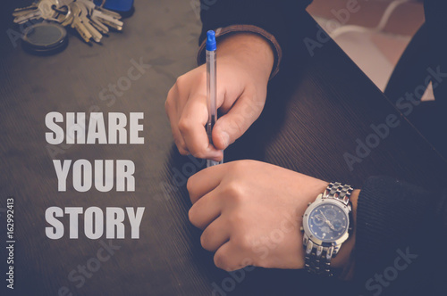 share your story on wooden table, businessman hands in office