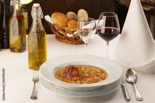 Bean soup arranged in a plate, Wineglass in background, Traditional dish in elegant setting, Selective focus with soft light