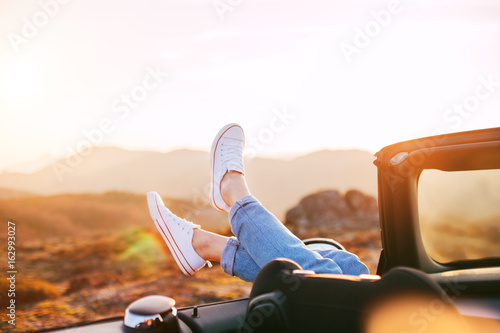 Happy woman rests and pushes her shoes out of the convertible to enjoy the view photo