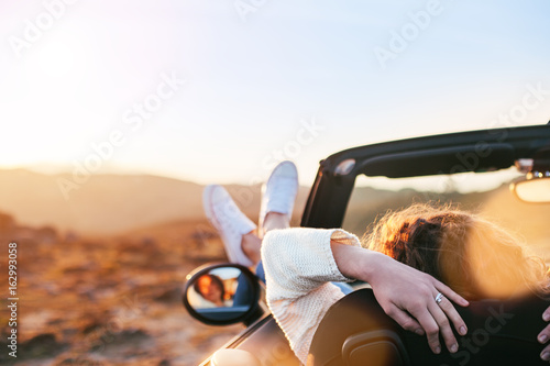 Young woman enjoying the sunset from a convertible photo