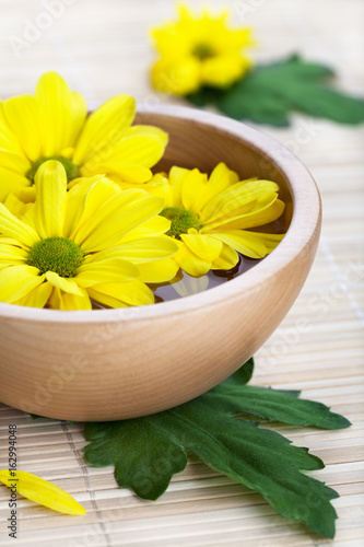 Yellow flowers in wooden bowl
