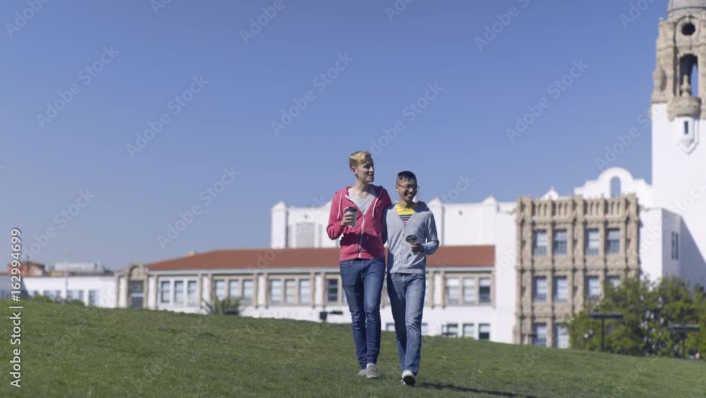 Gay Couple Drink Coffee And Walk Together Through Park, San Francisco Gay Couple Drink Coffee And Walk Together Through Park, San Francisco