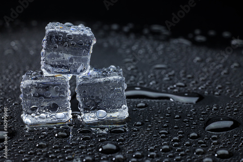 Wet ice cubes and water drop on black background.