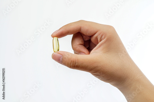 man's hand holding Fish oil capsules with omega 3 and vitamin D healthy diet concept, isolated on white background.