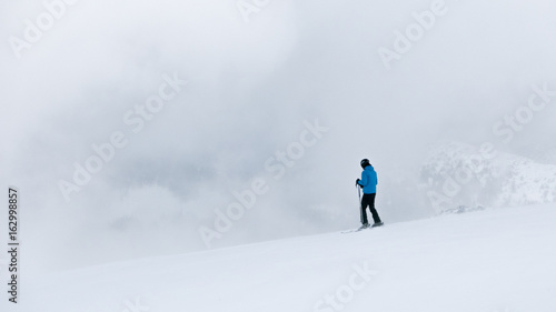 Skiers in thick fog on ski slope in ski resort.