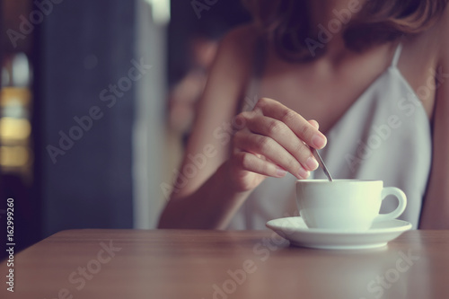 close up asian woman using little spoon brewing hot coffee for good taste in coffee bar shop,modern life style,hipster girl concept,vintage color filter