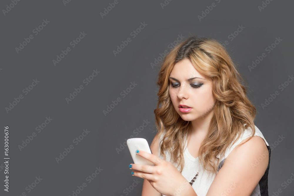Serious teenage girl concentrically looking at her smart phone Serious teenage girl concentrically looking at her smart phone