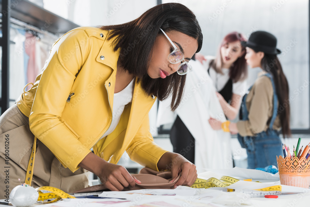 side view of confident fashion designer working with textile at workplace side view of confident fashion designer working with textile at workplace