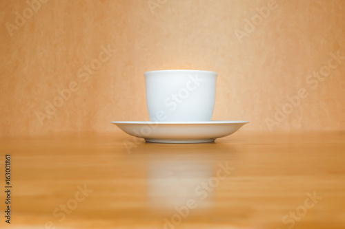 A white cup of coffee on wooden table.