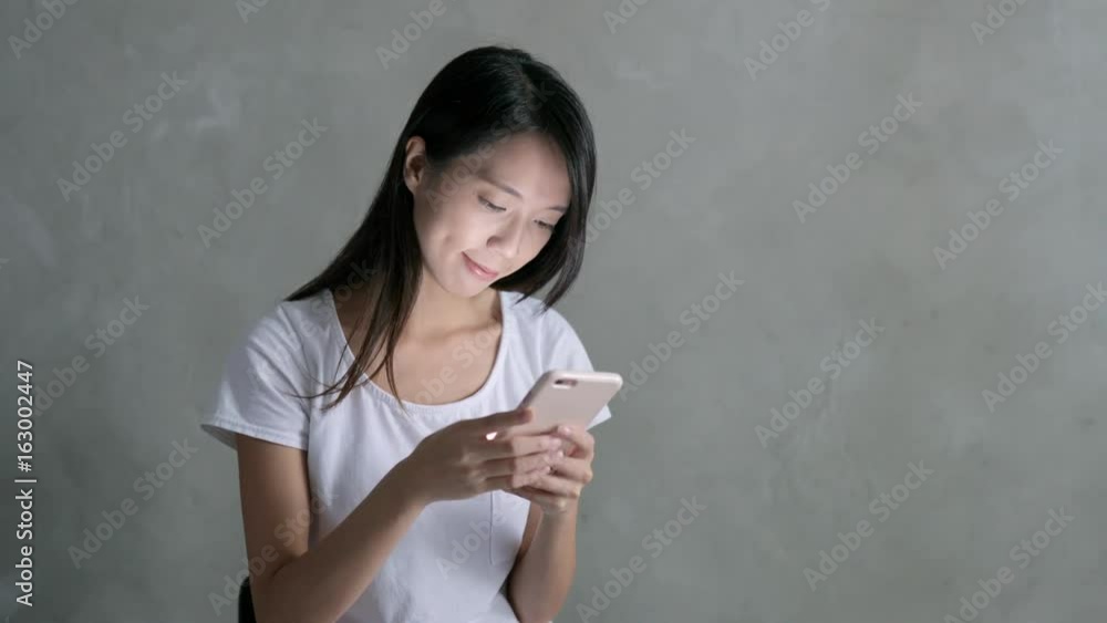 Woman use of smart phone over grey background Woman use of smart phone over grey background