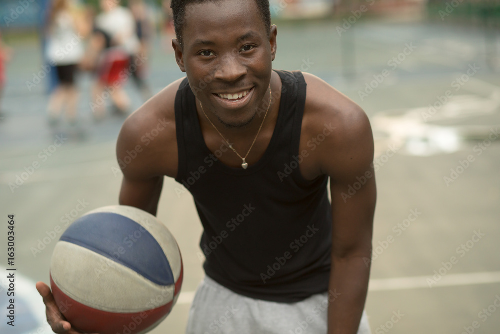 Portrait of smiling african american man on basketball court keep ball