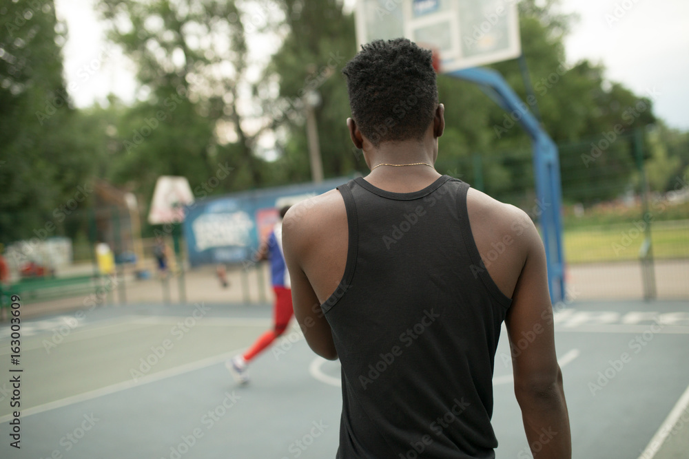 African american man plays on street basketball court. Back view. African american man plays on street basketball court. Back view.