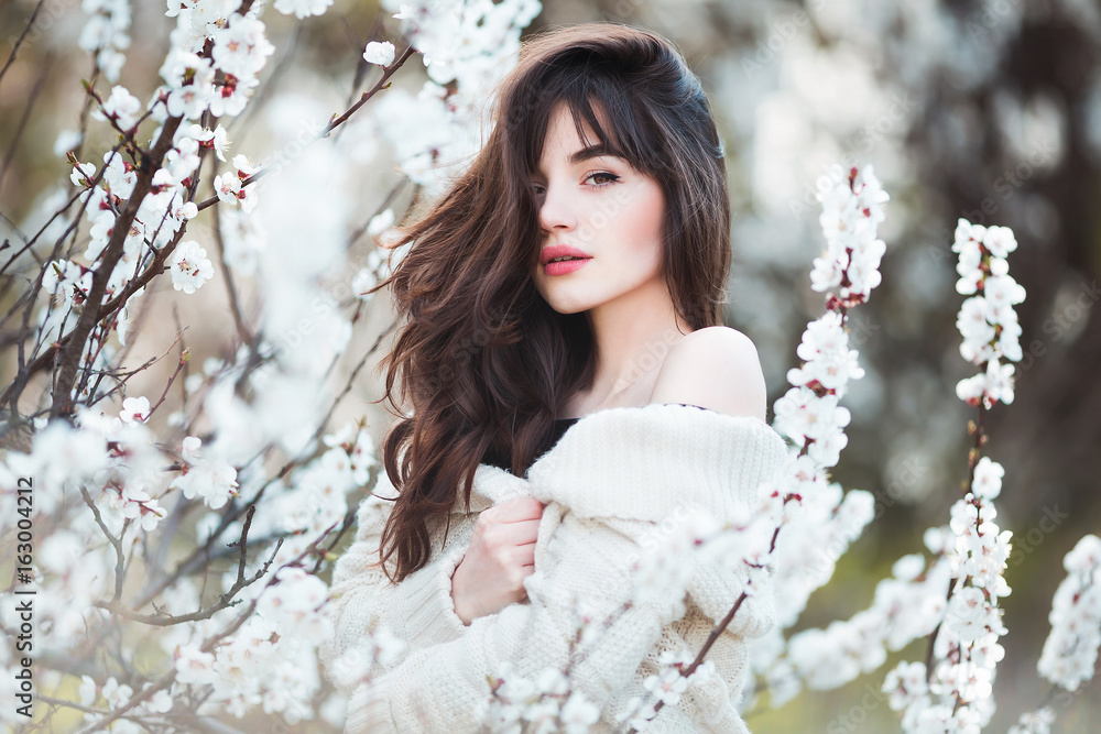 Happy beautiful young woman with long black healthy hair enjoy fresh flowers and sun light in blossom park. Happy beautiful young woman with long black healthy hair enjoy fresh flowers and sun light in blossom park.