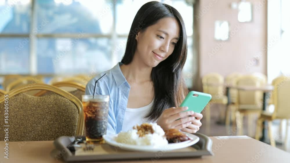 Woman using cellphone with her lunch in restaurant Woman using cellphone with her lunch in restaurant