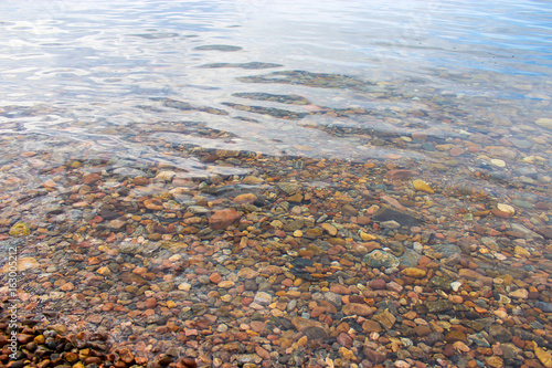 Pebbles and small stones on the seabed in a transparent and clean water. Texture, background